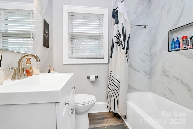 bathroom with vanity, wood finished floors, baseboards, toilet, and shower / tub combo with curtain