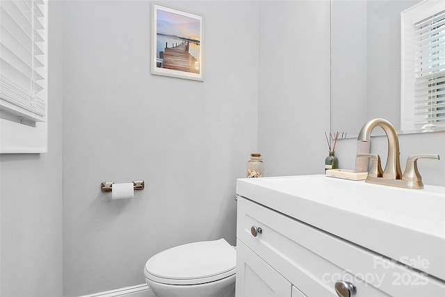 half bath featuring vanity, toilet, and baseboards