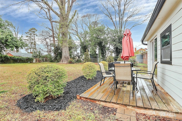 deck with outdoor dining space, a lawn, and a fenced backyard