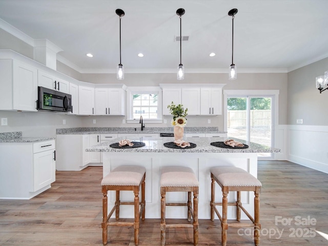 kitchen with a wealth of natural light, a kitchen bar, and ornamental molding