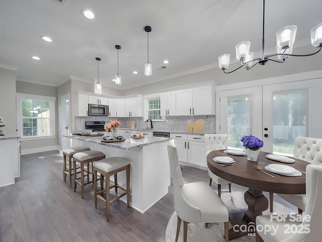 kitchen featuring stainless steel range with electric stovetop, a sink, french doors, white cabinets, and decorative backsplash