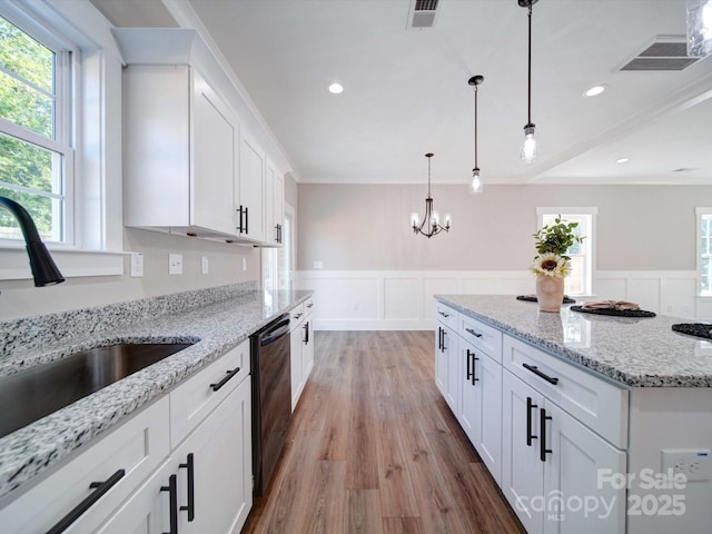 kitchen featuring dishwasher, a wainscoted wall, visible vents, and a sink