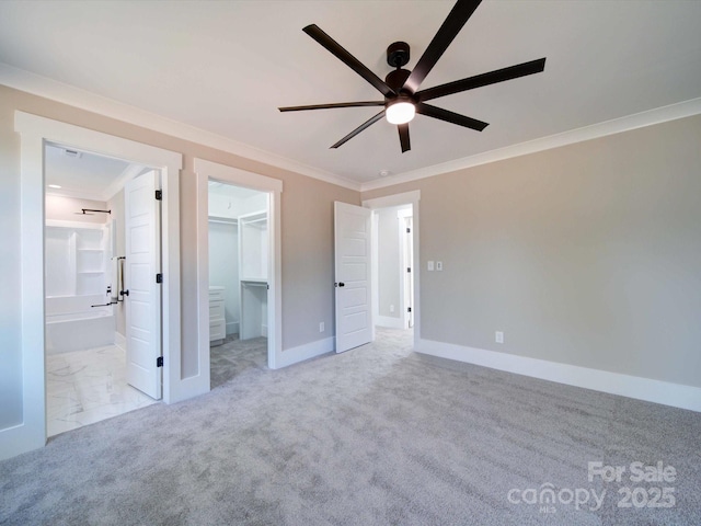 unfurnished bedroom with a walk in closet, ensuite bathroom, carpet, crown molding, and baseboards