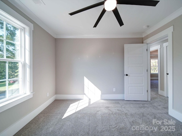 carpeted empty room with a ceiling fan, baseboards, and ornamental molding