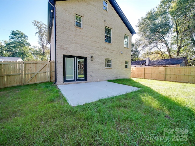 rear view of house with a patio area, a lawn, brick siding, and a fenced backyard