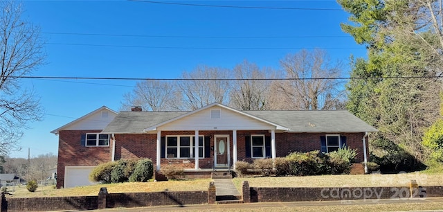 view of front of home featuring a chimney, brick siding, a porch, and an attached garage