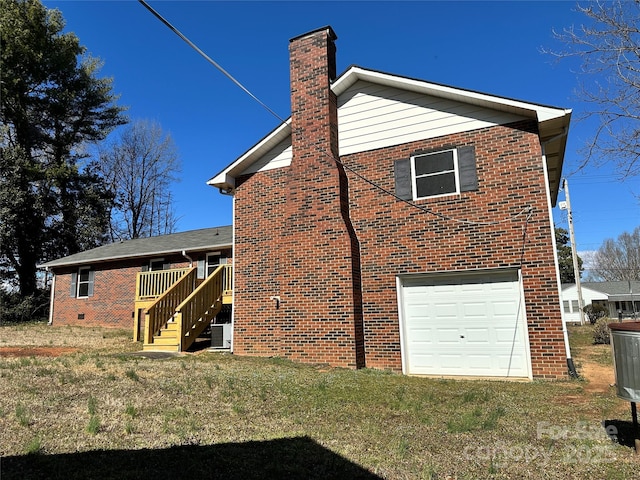 back of house featuring brick siding, a lawn, an attached garage, and a chimney