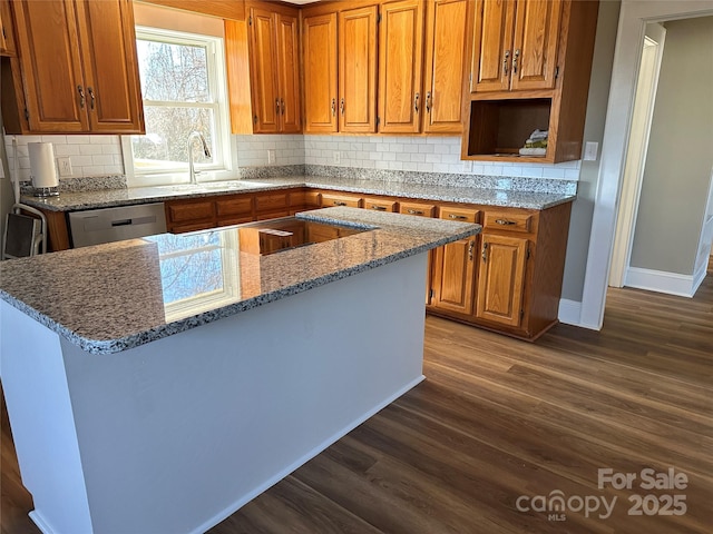 kitchen featuring brown cabinetry, backsplash, dark wood-type flooring, and a sink