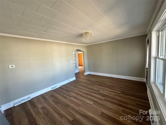 spare room featuring arched walkways, visible vents, baseboards, and dark wood-style flooring