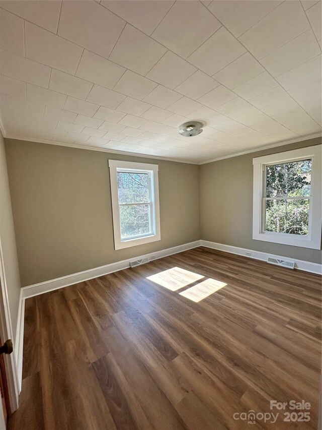 unfurnished room featuring visible vents, baseboards, dark wood-style floors, and crown molding