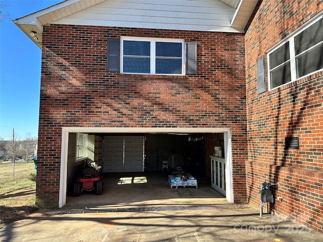 view of side of home with a garage, brick siding, and driveway