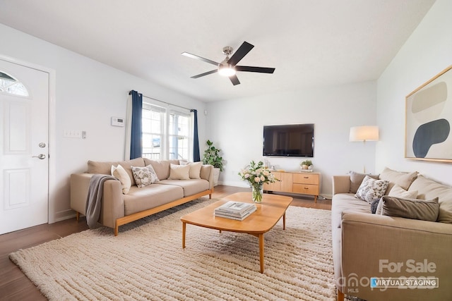 living area with baseboards, wood finished floors, and a ceiling fan