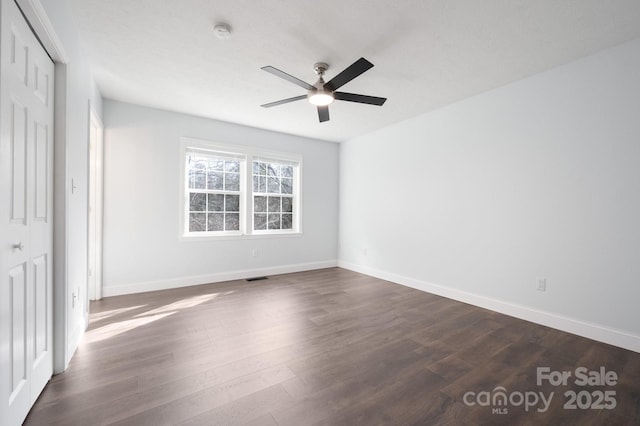 unfurnished bedroom featuring dark wood-type flooring, baseboards, ceiling fan, visible vents, and a closet