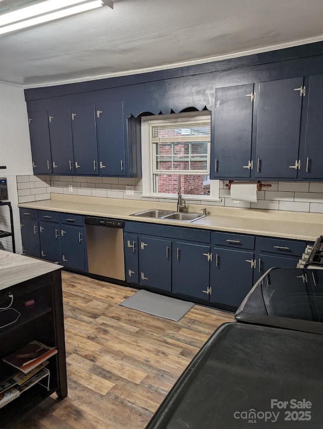 kitchen with a sink, blue cabinetry, wood finished floors, and stainless steel dishwasher