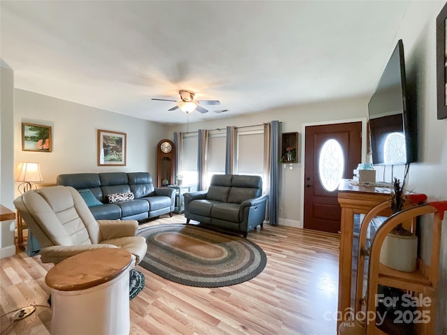 living area featuring a ceiling fan, visible vents, light wood-style floors, and baseboards