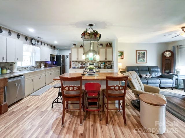 kitchen featuring a sink, stainless steel appliances, open floor plan, and light wood finished floors