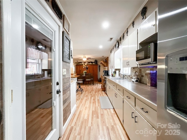 kitchen featuring light wood-style flooring, white cabinets, appliances with stainless steel finishes, and a sink