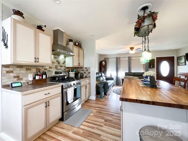 kitchen with wall chimney exhaust hood, open floor plan, stainless steel gas range, and butcher block counters