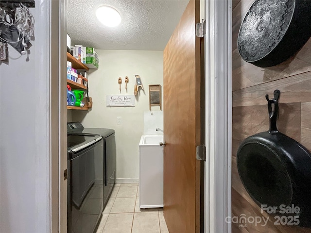 laundry area with light tile patterned floors, laundry area, separate washer and dryer, a textured ceiling, and a sink