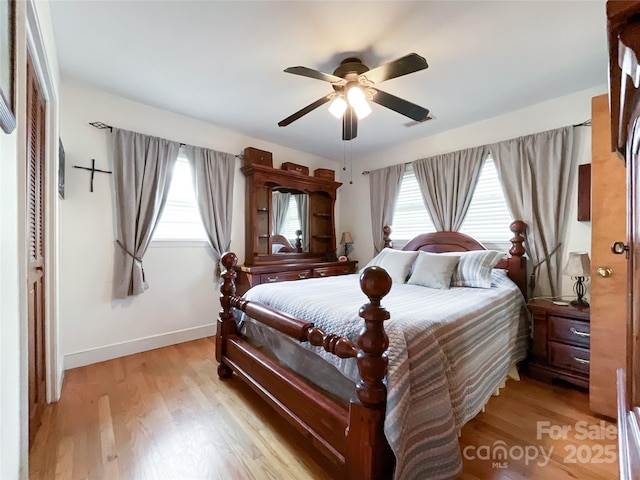 bedroom featuring visible vents, baseboards, light wood-type flooring, and ceiling fan