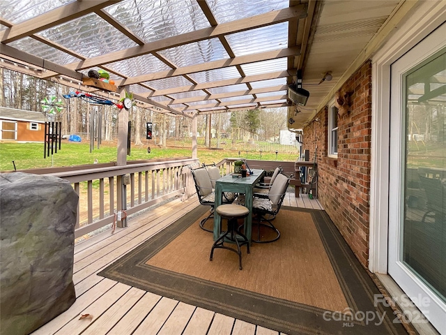 deck featuring a storage unit, a lawn, outdoor dining space, a pergola, and an outdoor structure