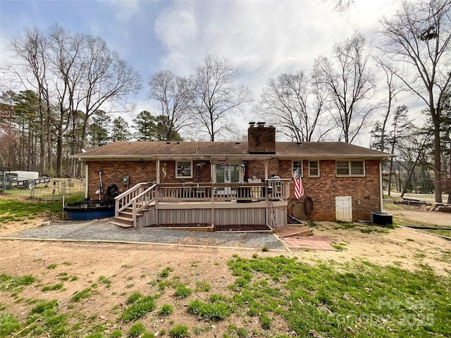 back of house featuring brick siding, a chimney, and a wooden deck