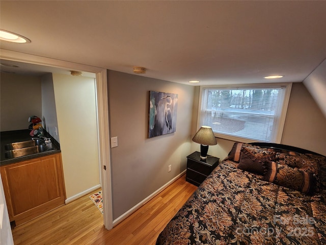 bedroom featuring light wood-style flooring, baseboards, and a sink