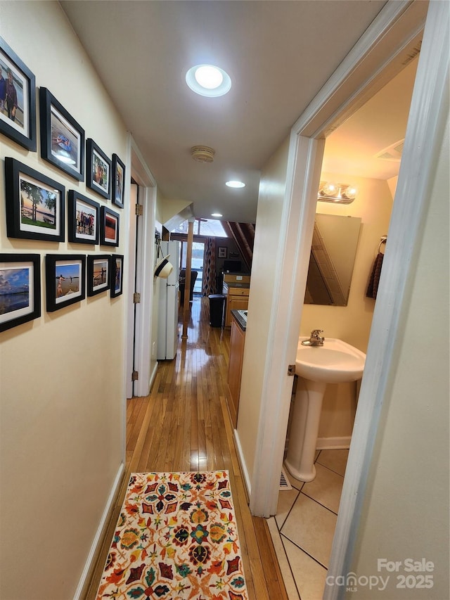 corridor featuring ornate columns, recessed lighting, baseboards, and wood-type flooring