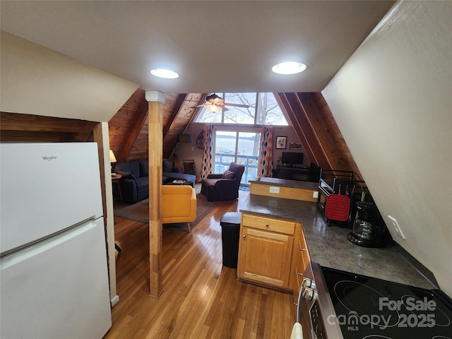 interior space featuring ceiling fan, light wood-style floors, and lofted ceiling