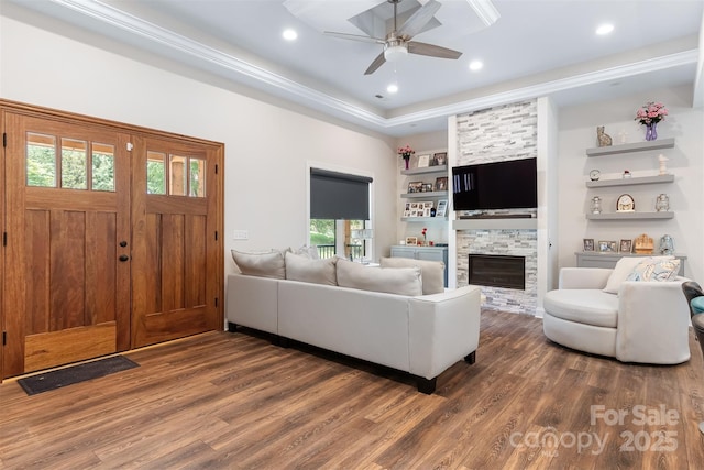 living room featuring built in shelves, a ceiling fan, wood finished floors, recessed lighting, and a stone fireplace