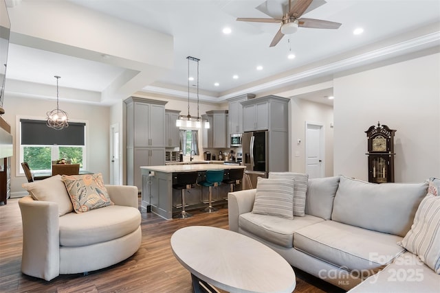 living area with recessed lighting, a raised ceiling, ceiling fan, and dark wood-style flooring