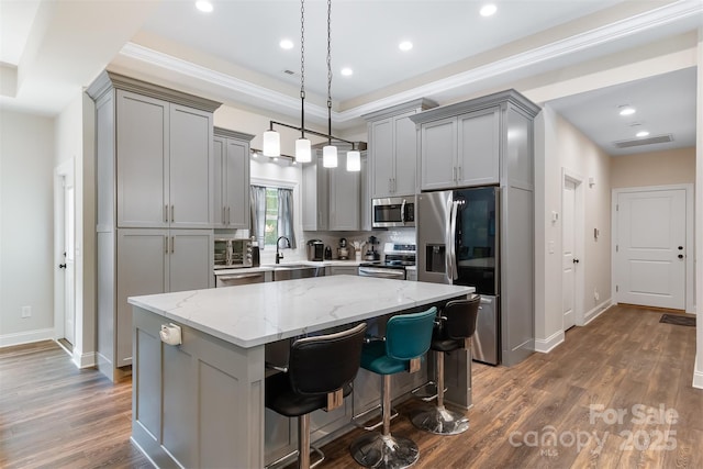 kitchen with visible vents, gray cabinets, a sink, stainless steel appliances, and a center island