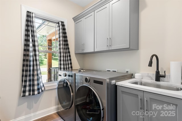 washroom featuring baseboards, washer and clothes dryer, wood finished floors, cabinet space, and a sink