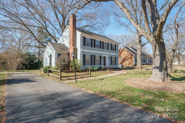 view of front of property with a front yard, a chimney, and fence