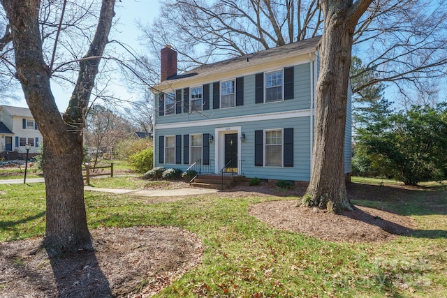 colonial inspired home featuring a front lawn and a chimney