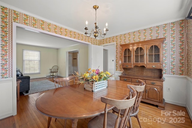 dining room featuring light wood-style floors, an inviting chandelier, and wallpapered walls