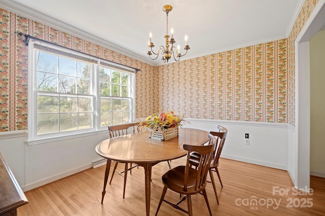 dining area featuring a wainscoted wall, a notable chandelier, light wood-style floors, and baseboards