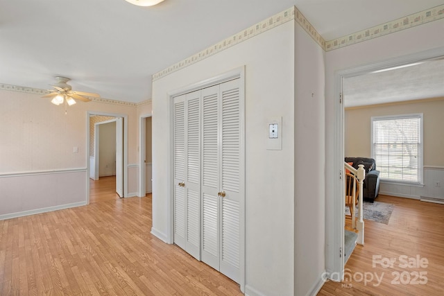 corridor featuring light wood-type flooring and baseboards