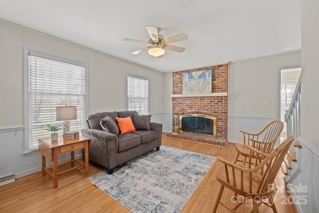 living area featuring visible vents, a brick fireplace, ceiling fan, and wood finished floors