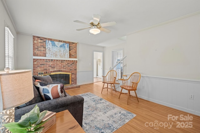 living area with wainscoting, a healthy amount of sunlight, wood finished floors, and a fireplace