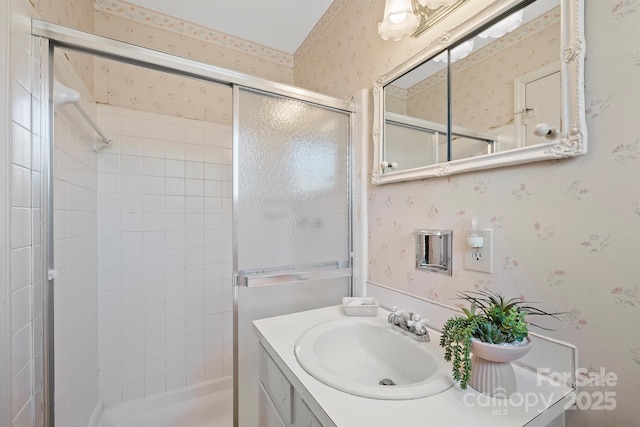 full bath with a stall shower, wallpapered walls, and vanity