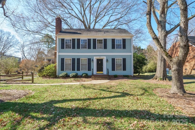 colonial house with a chimney and a front yard