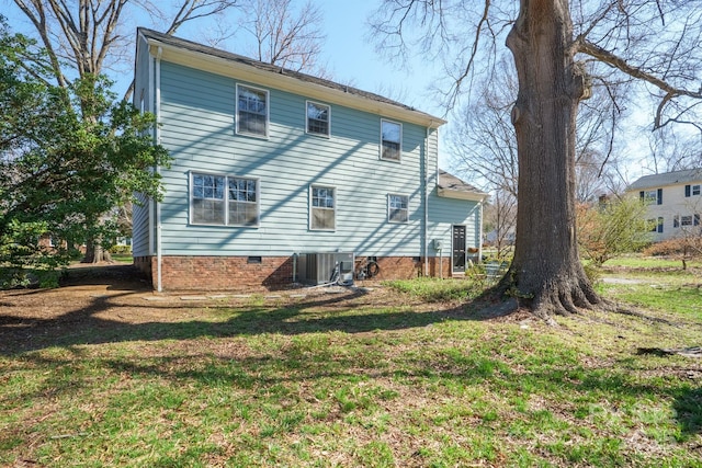 rear view of property featuring central air condition unit and a yard