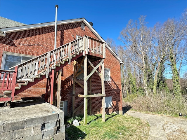 view of side of home with stairway and brick siding