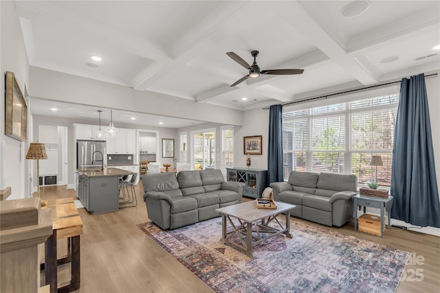 living area with light wood finished floors, coffered ceiling, and a wealth of natural light