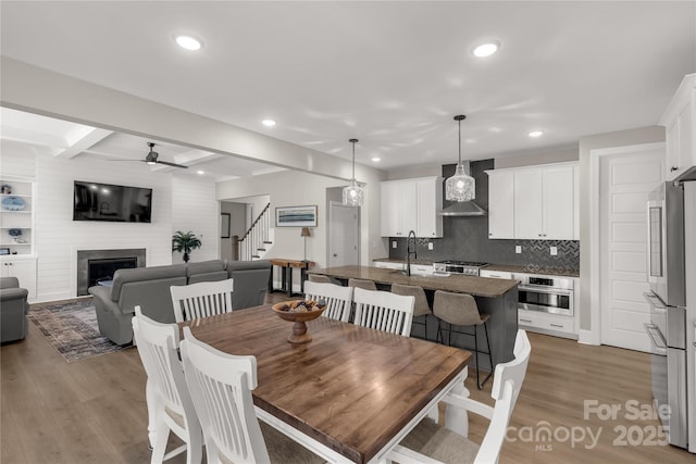 dining area with stairway, wood finished floors, a fireplace, recessed lighting, and ceiling fan