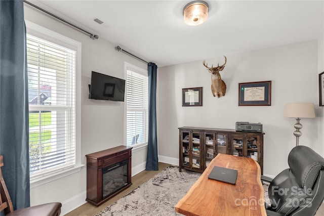 office with a glass covered fireplace, wood finished floors, and baseboards