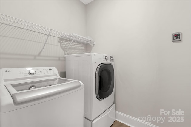 clothes washing area with laundry area, independent washer and dryer, and baseboards