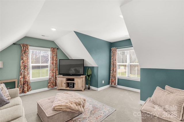 carpeted living area featuring a healthy amount of sunlight, lofted ceiling, and baseboards