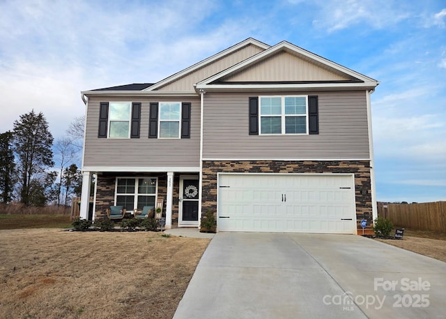 view of front of home with stone siding, driveway, a garage, and fence